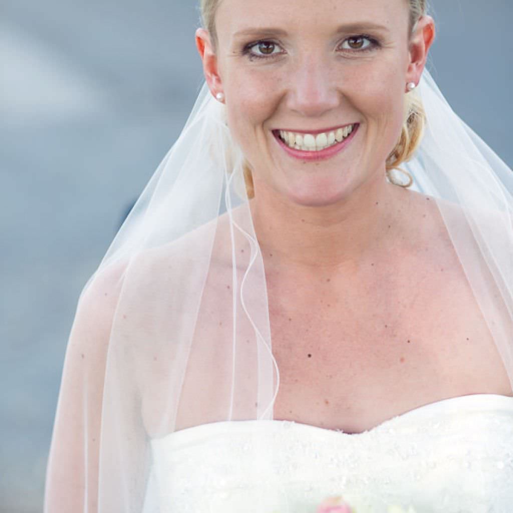 Strahlende Braut mit Schleier und schulterfreiem Brautkleid bei einer Hochzeit im Romantik Hotel Platte.