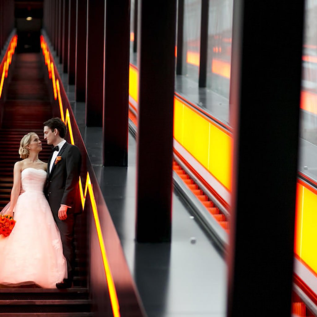 Das Brautpaar einer Hochzeit in der Zeche Zollverein in Essen steht auf einer langen Rolltreppe.