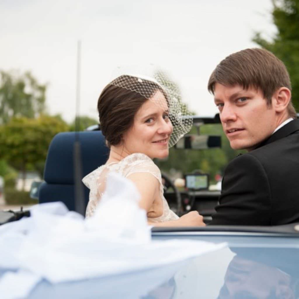 Hochzeitspaar einer Marathon Hochzeit in Dortmund posiert im Brautauto.