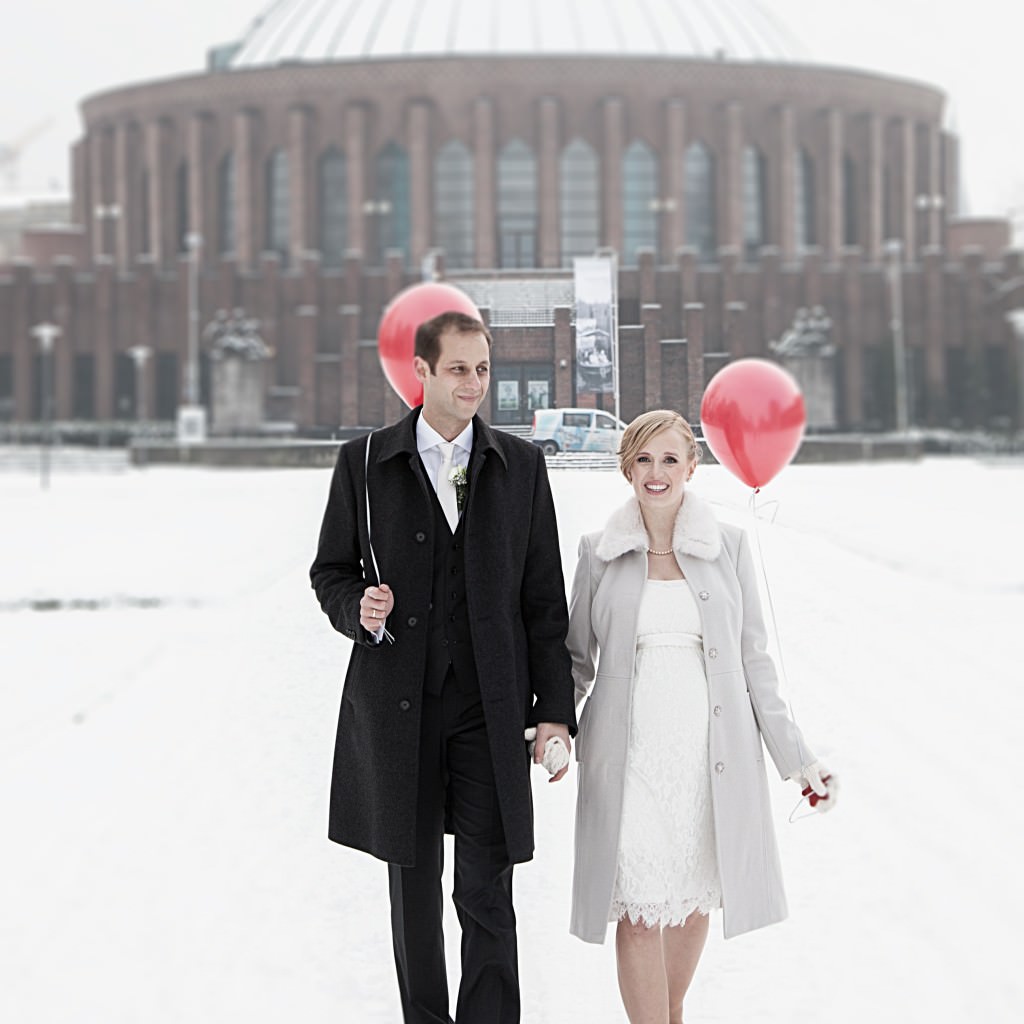 Das glückliche Brautpaar einer Winterhochzeit posiert im Schnee für Paarbilder.