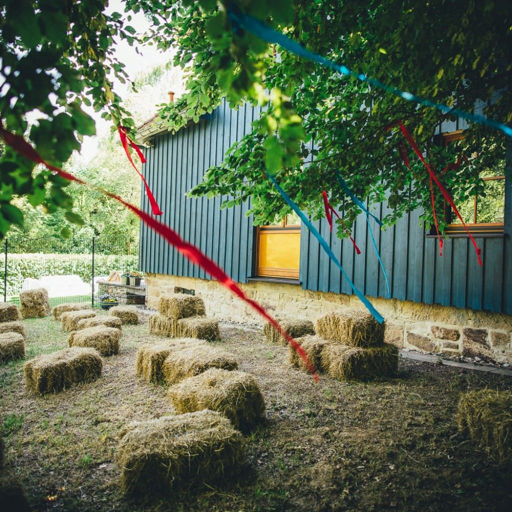 Heuballen als Sitzgelegenheit bei einer rustikalen Sommerhochzeit auf dem Bauernhof.