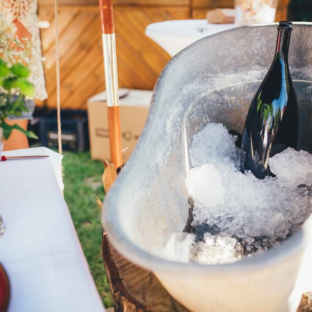 Mit Eiswürfeln gekühlte Sektflasche bei einer heißen Sommerhochzeit auf dem Bauernhof.