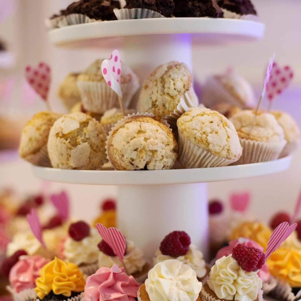 Köstliche Cupcakes von Café Sweet Time, angerichtet auf einer weißen Tortenplatte.