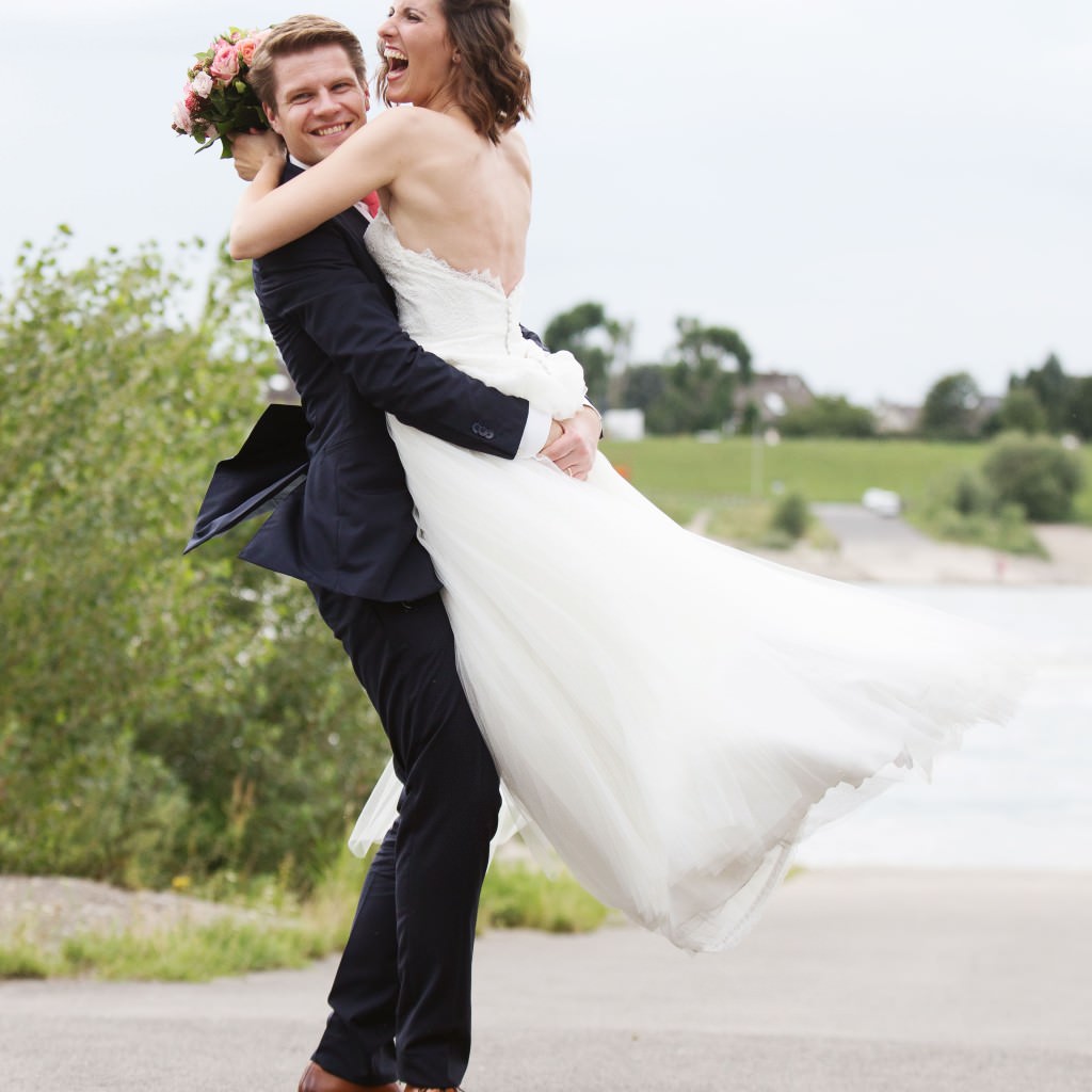 Das glückliche Brautpaar macht ausgelassene Outdoor Paarfotos bei ihrer Traumhochzeit auf Schloss Meierhof.