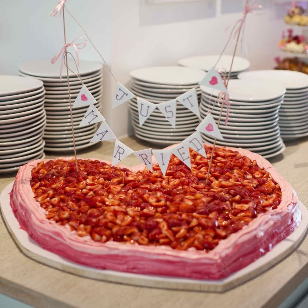 Rosafarbene Herz Hochzeitstorte mit Erdbeeren und just married Wimpelkette.