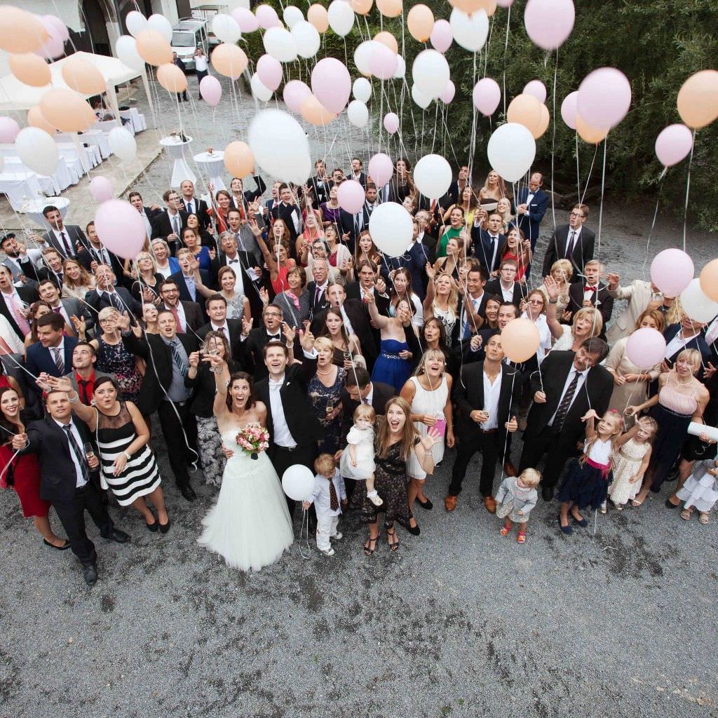 Hochzeitsgruppenfotoidee: Gäste und Brautpaar lassen bei der Traumhochzeit auf Schloss Meierhof Luftballons steigen.