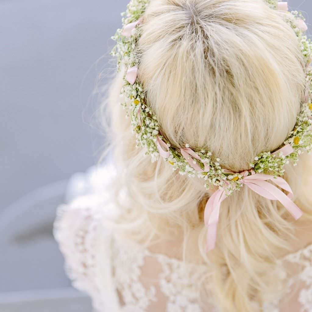 Die Braut trägt offene Haare und einen zauberhaften Midsommar-Haarkranz mit Schleierkraut.