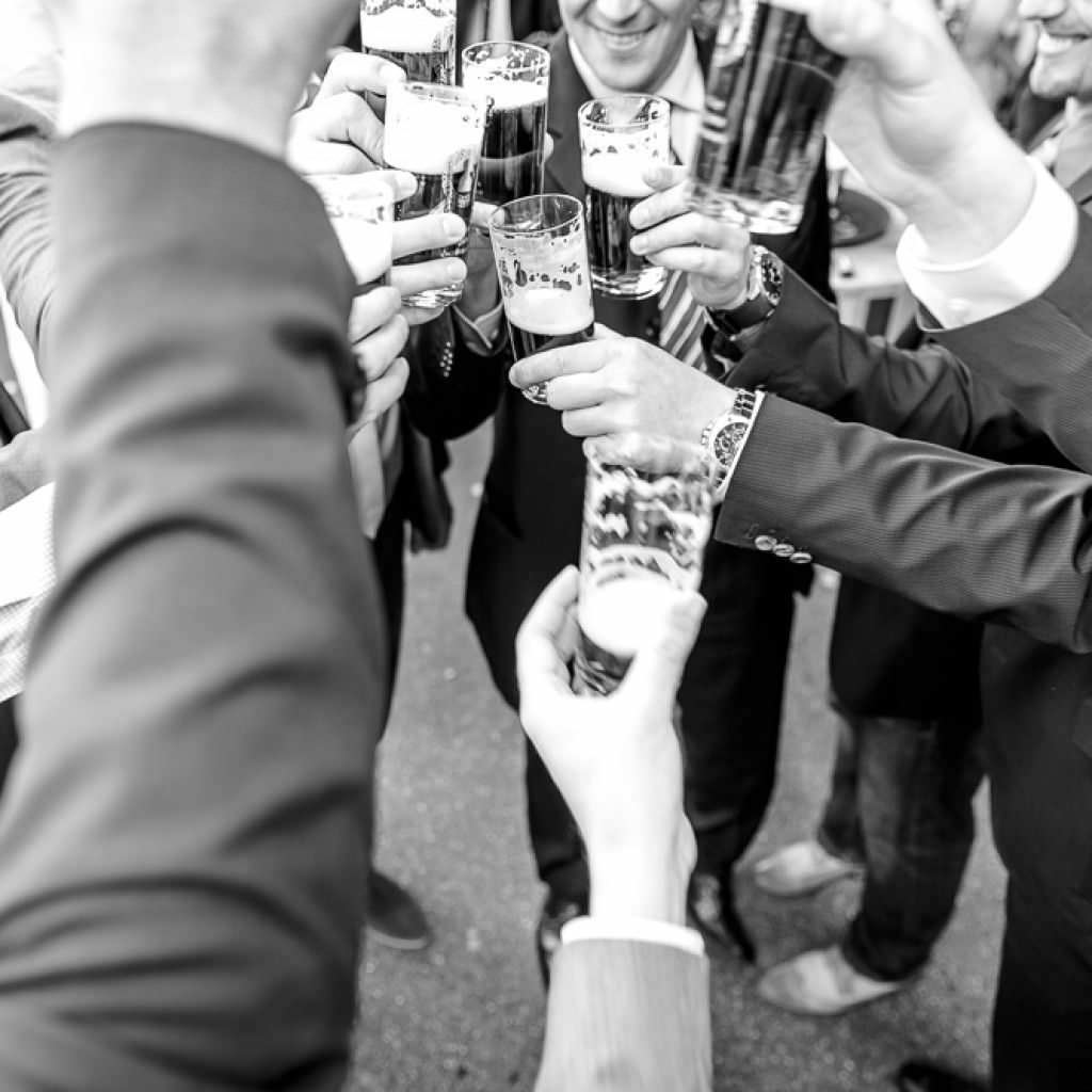 Die Gäste einer Scheunenhochzeit in Düsseldorf stoßen mit Bier an.