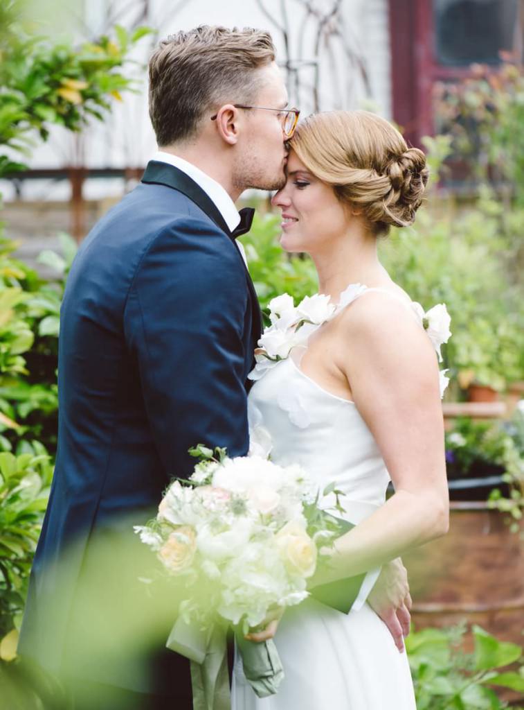 Romantisches Paarfoto: Der Bräutigam küsst die Braut zärtlich auf die Stirn