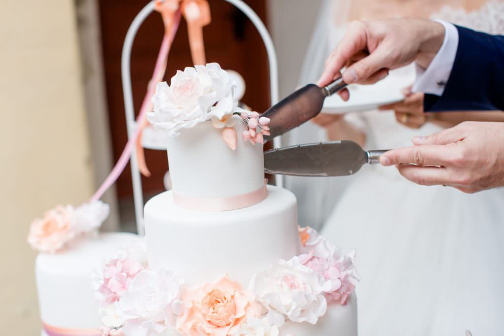 Das Brautpaar schneidet eine Hochzeitstorte mit Fondant an