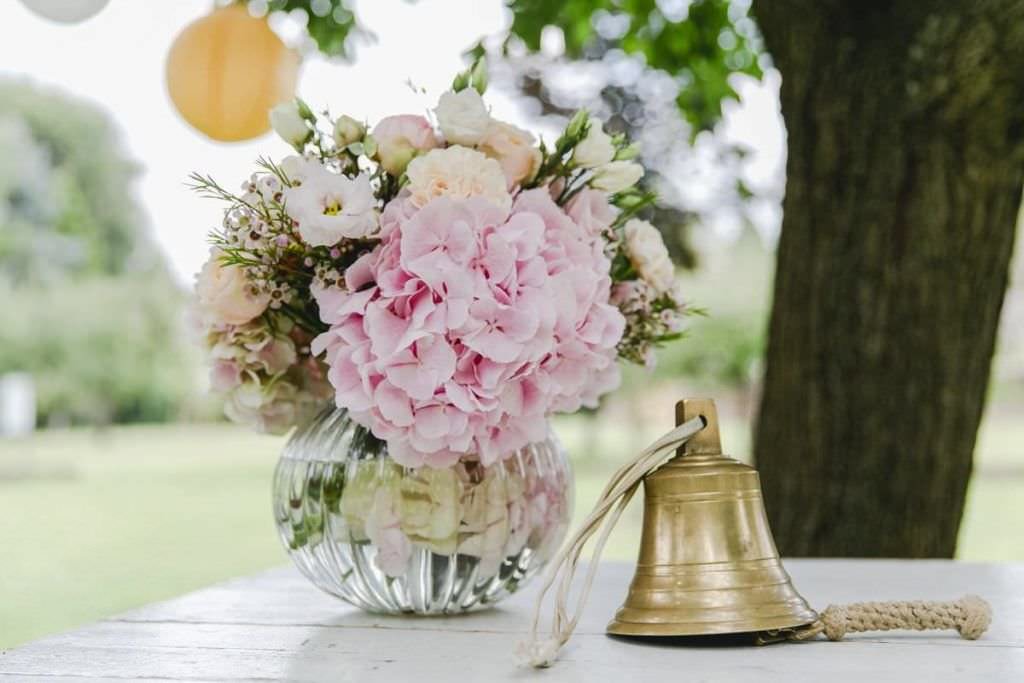 Blumendeko und Glocke als Hochzeitsdeko bei einer Freien Trauung im Kastanienhof in Köln