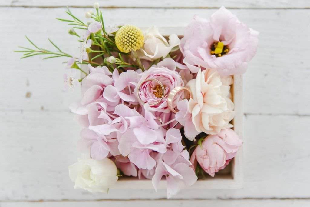 Hochzeitsfotoidee: Trauringe auf pastellfarbenen Blumen