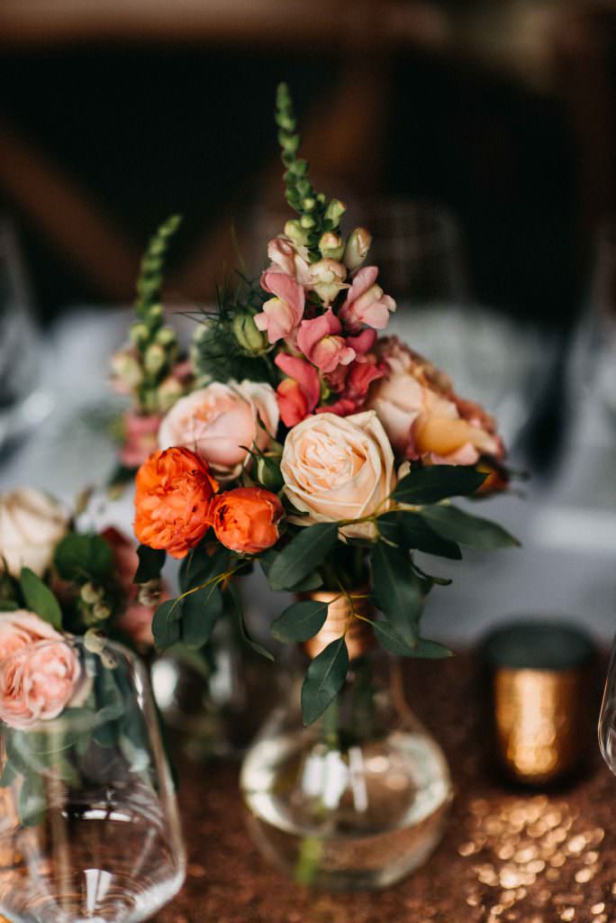 Hochzeit Gut Hohenholz: Tischdeko mit Blumen in Orange und Rosa