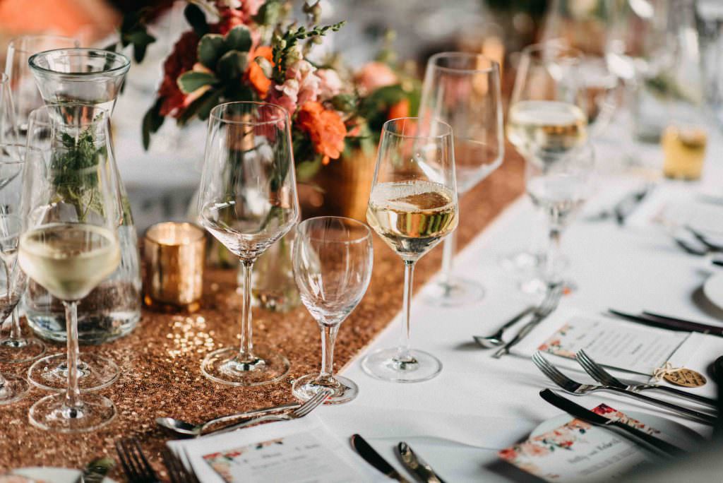 Hochzeitstischdeko mit Tischläufer in Kupfer und Blumen in Orange und Rosa