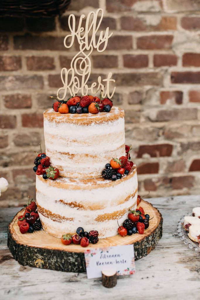 Hochzeit Gut Hohenholz: Rustikale Hochzeitstorte mit frischen Beeren und Cake Topper