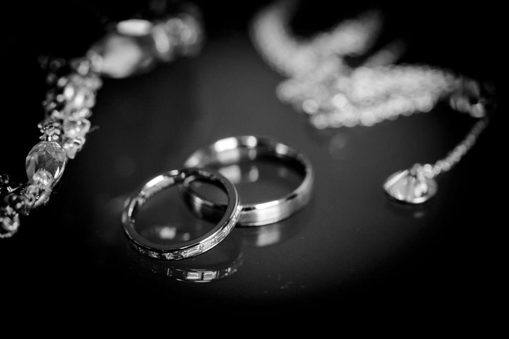 Schwarz-Weißes Hochzeitsfotos von den Trauringen neben Schmuck mit Diamanten
