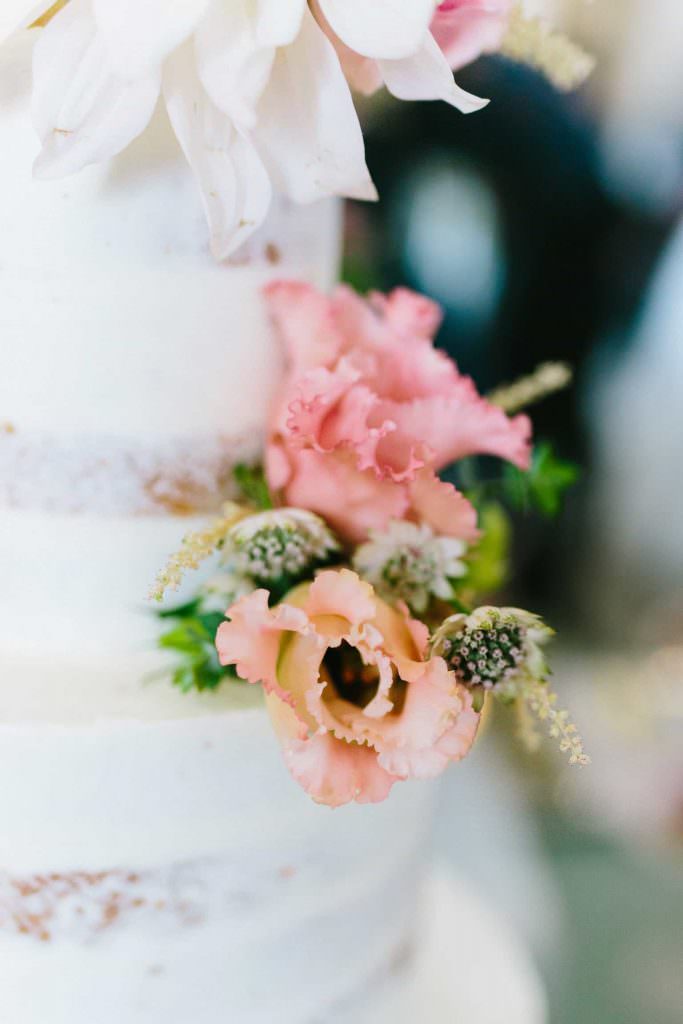 rosafarbene Blumendeko auf einer weißen Hochzeitstorte