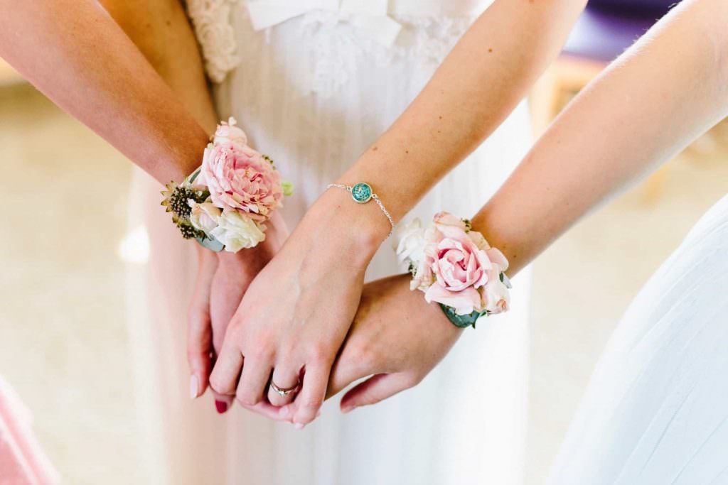 Brautarmband am Arm der Braut und Blumenschmuck am Arm der Brautjungfern