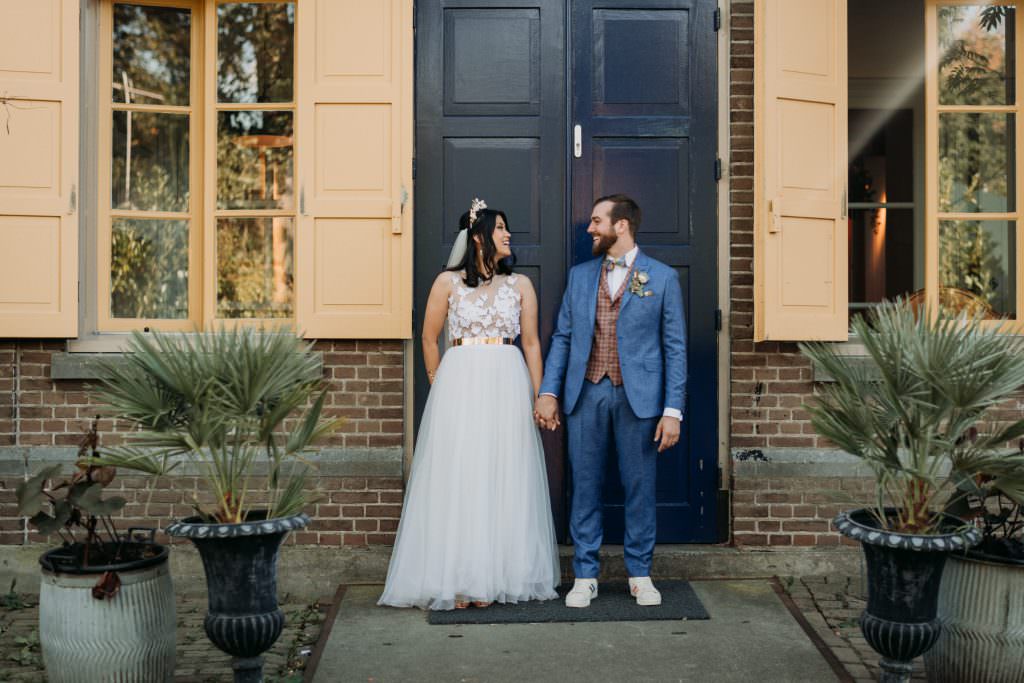 Originelles Hochzeits-Paarfoto vor einer blauen Haustür