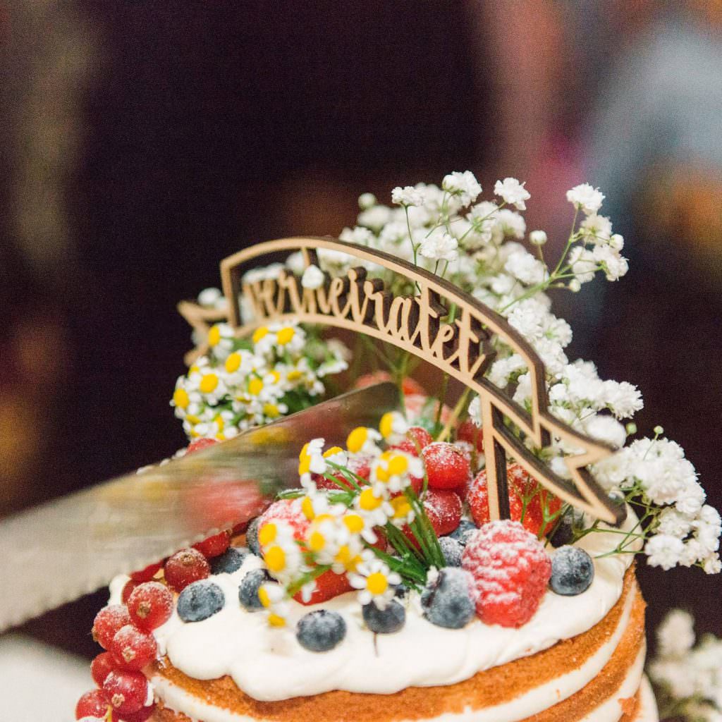 eine Hochzeitstorte mit verheiratet Cake Topper wird angeschnitten