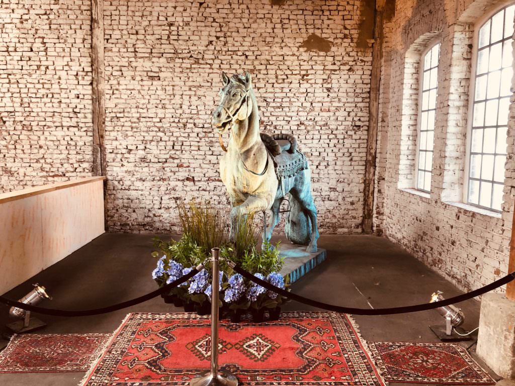 Hochzeitslocation Chapelle de Nüss – Blumenbouquet vor einer Vintage Pferdestatue als Deko