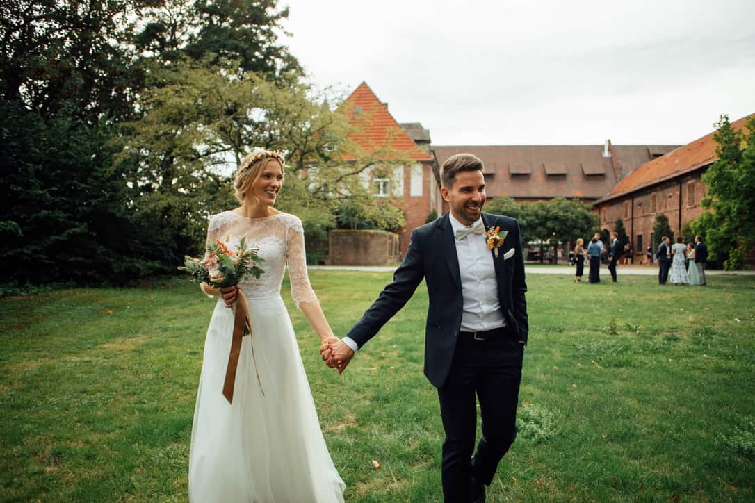 Das Hochzeitspaar Hand in Hand auf einer Wiese von Gutshof Ladenburg