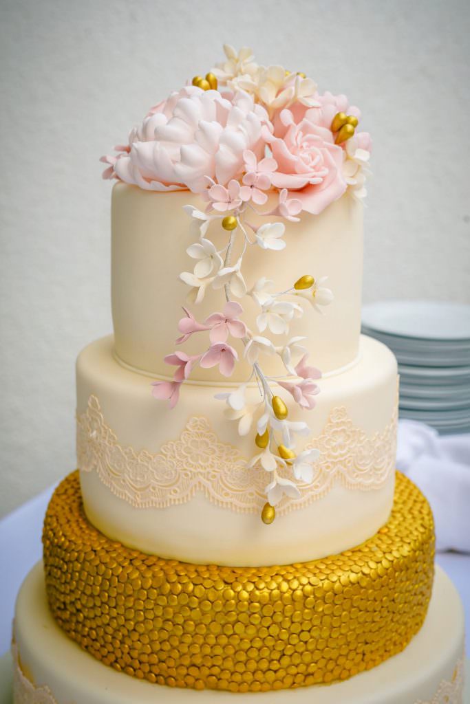 Cremefarbene Hochzeitstorte mit Fondant, Blumendeko und Gold Details