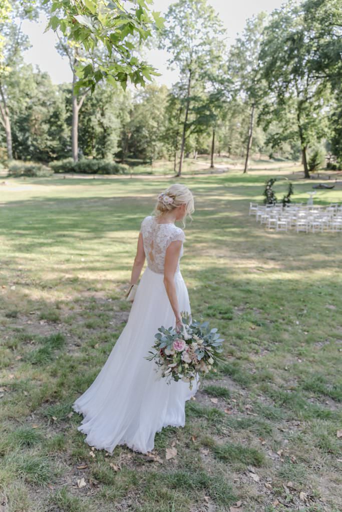 die Braut trägt ein hochgeschlossenes Brautkleid mit Spitze und langem Rock