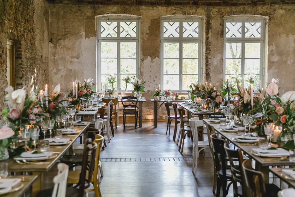 Corona-Hochzeit Rittergut Orr Festsaal mit rustikalen Holztischen und moderner Blumendeko.