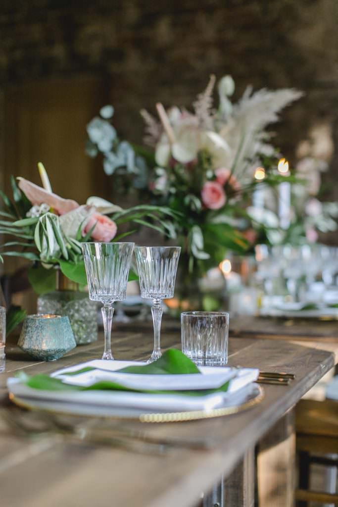 Hochzeitstischdeko mit Kristallgläsern, Blumen in Rosa und viel Greenery.