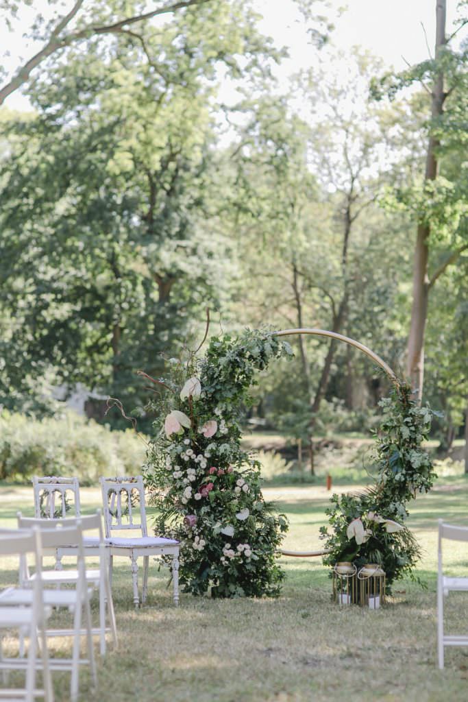 Corona-Hochzeit Rittergut Orr: Freie Trauung auf der Wiese mit Greenery Traubogen und weißen Stühlen