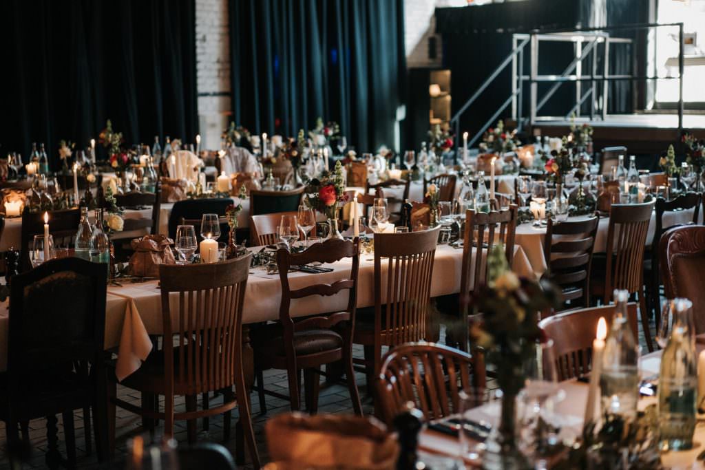 Seifenfabrik Düsseldorf Festsaal mit rustikalen Holzstühlen und gedeckten Hochzeitstischen