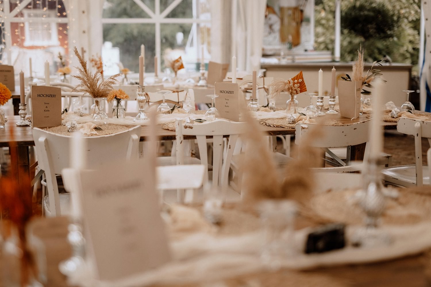 Hochzeitsfeier mit weißer Tischdeko im Boho-Stil und shabby Holzstühlen