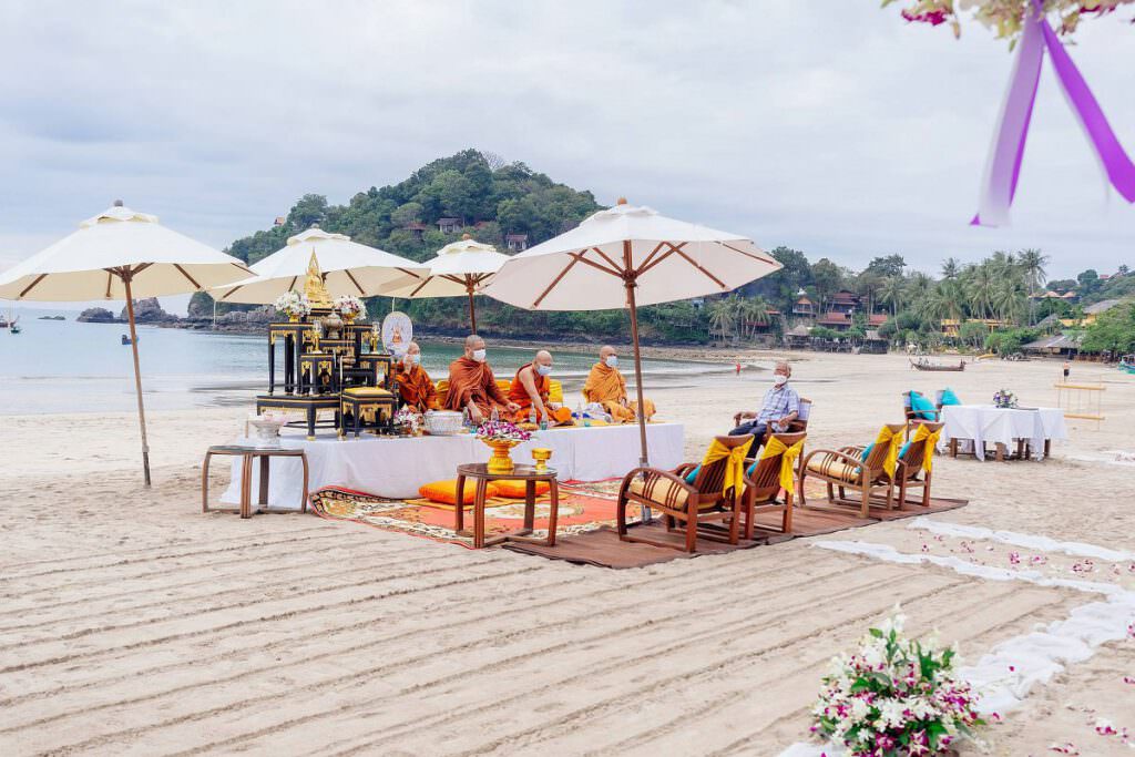 Blick auf eine Terrasse am Meer in Thailand. Auf der Terrasse stehen Sonnenschirme mit Liegen darunter. Im Vordergrund ist noch etwas Hochzeits-Dekoration zu sehen.