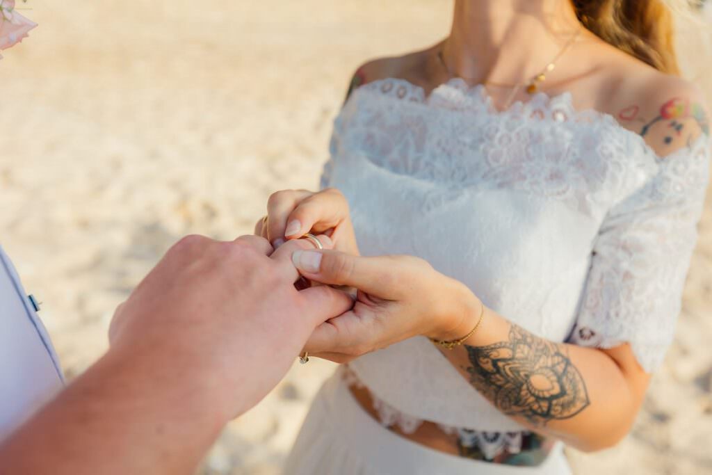 Ein Brautpaar am Strand. er steckt ihr den Trauring auf den Finger.