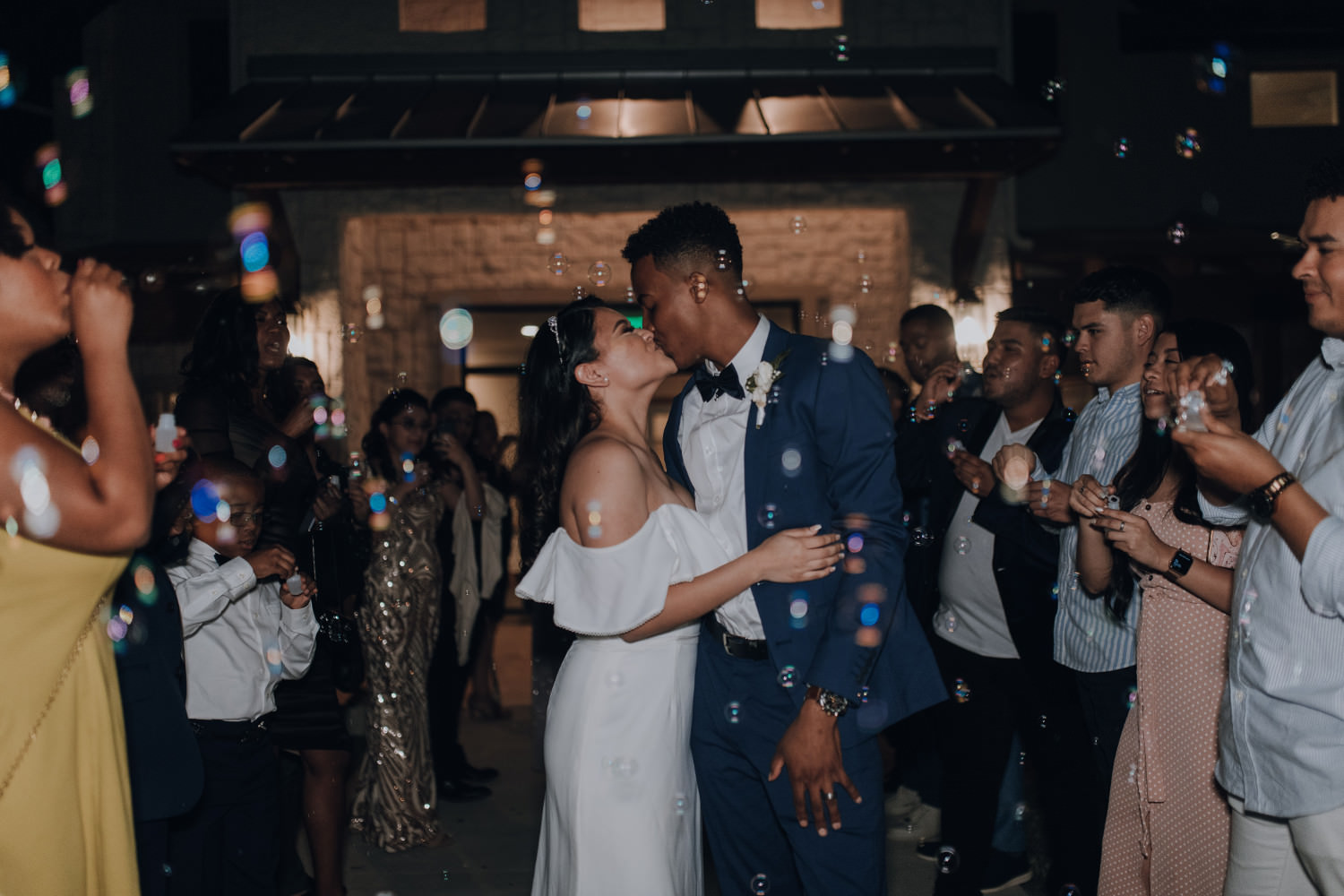 das Brautpaar küsst sich beim Hochzeitstanz umgeben von Seifenblasen und Hochzeitsgästen